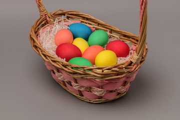 Fototapeta na wymiar Basket with nine colorful Easter eggs on a gray background. Horizontal photography