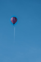 Hot Air Balloon flying under a Passenger Jet in a clear blue sky