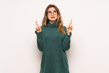 Teenager girl over white wall with fingers crossing and wishing the best