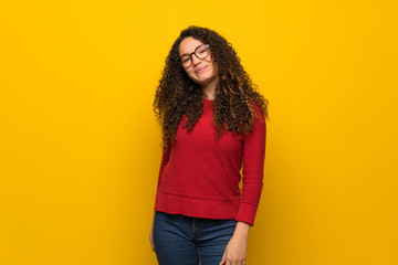Teenager girl with red sweater over yellow wall with glasses and smiling