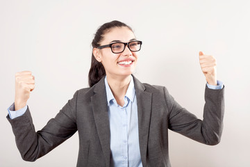 Success in business or career. Enthusiastic businesswoman with raised arms cheering in isolated on grey background