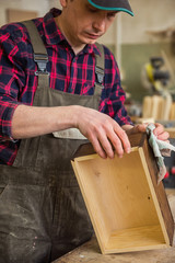 Carpenter painting wooden board in a wooden workshop. Profession, carpentry and woodwork concept.