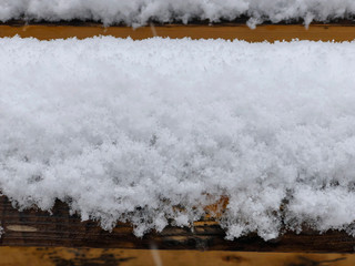 Snow lying on the bench. Snow on the streets of the city. The beginning of winter