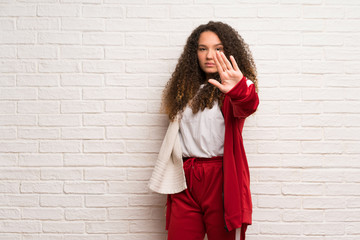 Teenager sport girl with curly hair making stop gesture denying a situation that thinks wrong