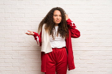Teenager sport girl with curly hair making the gesture of madness putting finger on the head
