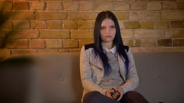 Closeup shoot of young pretty caucasian female watching TV at home being sensitive and crying sitting on the couch indoors