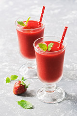 Healthy vegan strawberry smoothie in glasses on a gray background. Summer strawberry smoothie. Selective focus.