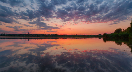 Ukrainian summer sunset landscape with cloudy sky reflected by still water