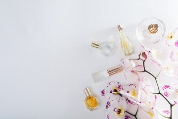 Bottles of perfume with white orchid with purple spots on white background. Space