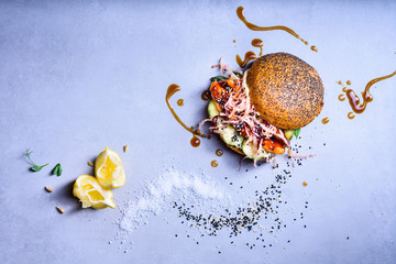 Salmon fish burger with with coleslaw and cucumber. Healthy diet concept.