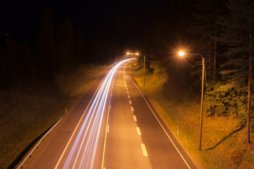 Obraz premium Long exposure photo of traffic with blurred traces from cars at night in Finland, top view.
