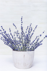 Natural lavender flowers in round vase on wood with copy space. Rustic flowerpot. Selective focus.