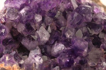 Beautiful amethyst druse close-up on white cement background. Semi precious gem used for jewels.