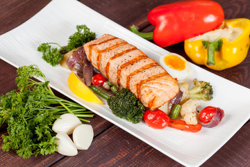  appetizing fried fish, beautifully laid out with greens and vegetables on a dish, for designer solutions in cooking