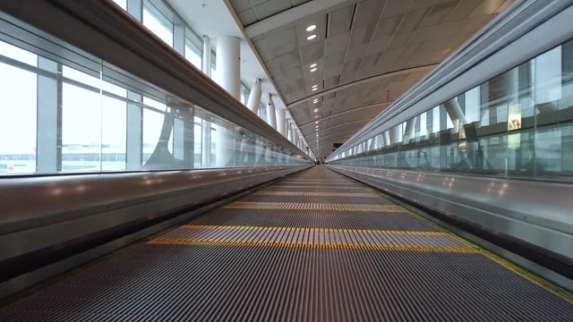 ThyssenKrupp Express Walkway at Toronto Pearson airport. High speed travelator at arrivals next to planes on tarmac. Passengers moving fast on moving walkway.