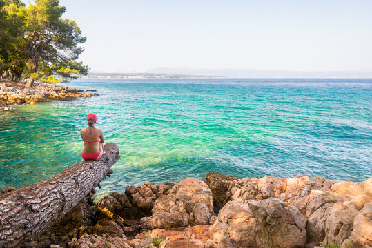 Young woman on a beach enjoying the view near Malinska on island Krk, Croatia. Travel adventure and freedom concept. Copy space female looking view of sea background.