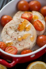 Close-up of baked hake medallions with cherry tomatoes, selective focus, vertical shot