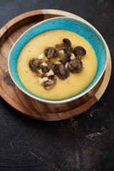 Bowl of polenta with fried mushrooms and cheese, elevated view over dark brown stone background