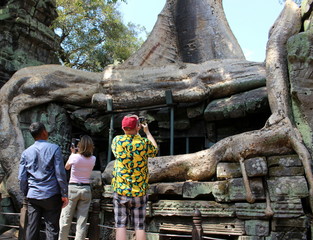 Tourists take pictures of giant tree roots in the temple Ta Prohm in Angkor, Cambodia
