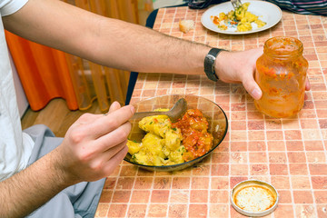 Man at the table in the kitchen eating potatoes