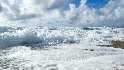 A ground view of waves crashing onto the beach in Florida's Atlantic Ocean on a beautiful cloudy day.