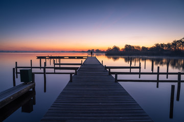 Man on a jetty  enjoying a tranquil dawn at the Leekstermeer, Holland.