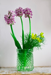 Three purple and three yellow spring flowers in a small vase.