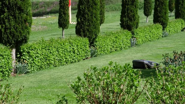 View from the street of luxury green garden with working in silence auto mower an mobile smart home controlled autonomous mower