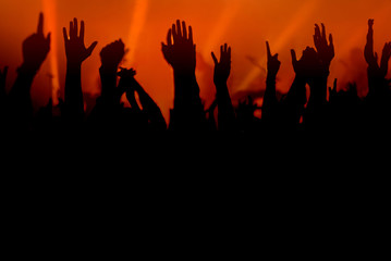 Hands silhouettes of the crowd raised up at music show. Colorful background