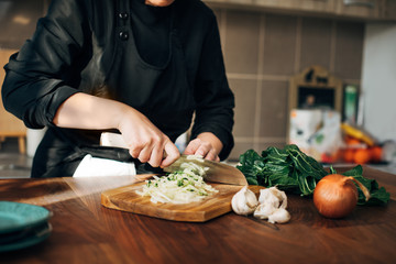 Female chef chopping raw vegetables on a wooden board