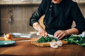 Female chef chopping raw vegetables on a wooden board