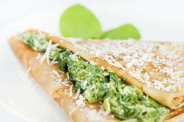 Thin delicious pancake with spinach on white
