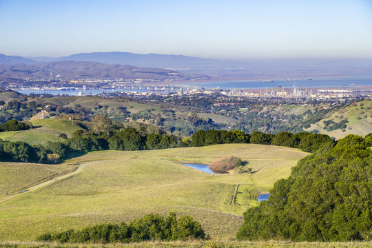 Green rolling hills in Briones Regional Park and Pollution over Suisun Bay in the background, Contra Costa county, San Francisco east bay, California