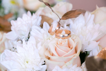 Wedding rings on a bouquet. Wedding bouquet of white and golden roses. Wedding in golden colors