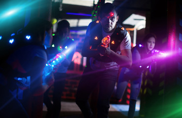 Excited guy laser tag player in bright beams - obrazy, fototapety, plakaty