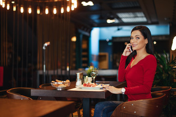 Young woman on breakfast talking on the phone in a restaurant