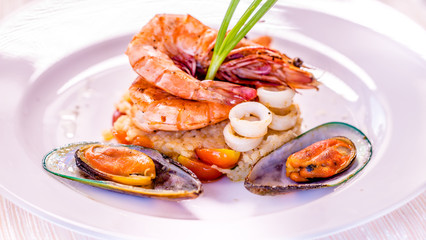 Fine dining mixed seafood set on the white plate, Shrimps, squids, green mussels