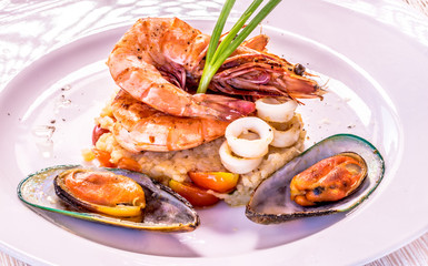 Fine dining mixed seafood set on the white plate, Shrimps, squids, green mussels