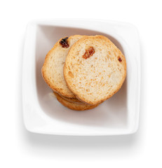 Mini round toasts of bread with raisins in white bowl. Top view. Isolated on white background.