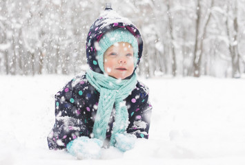 Fototapeta na wymiar Baby in a winter jumpsuit rejoices in the first snow