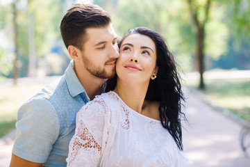 Obraz premium Portrait of a cute couple having fun in the park. Beautiful girl with long curly hair, loving family