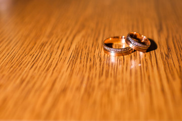 a pair of gold wedding rings on a wooden surface