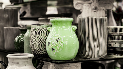 Multiple ceramic pots in B&W with one green pot