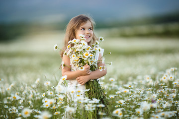 Little cute girl with bouquet of camomile flowers