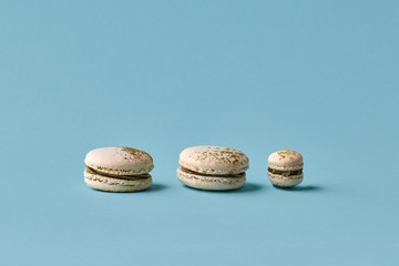 White macarons cake with colorful powder, top view, flat lay, sweet macaroon on blue background. Different size cookies