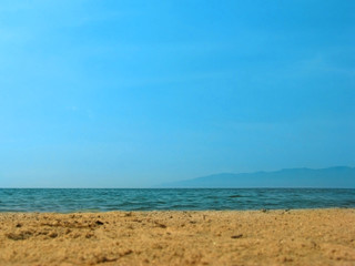 Empty sea beach background. Low horizon with sky and yellow sand. Silhouette of the mountains.