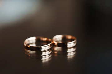 Close up view of stylish gold wedding rings on the dark wooden table