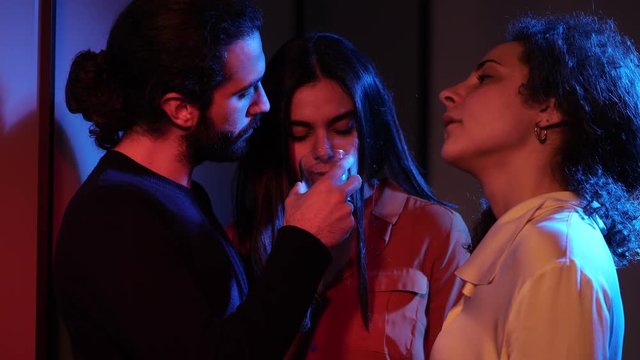 Three people drinking,flirting in the dark night club.Polygamy, threesome