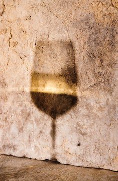 Shadow and reflection of wine glass on plaster wall