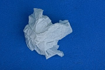 one piece of crumpled white paper lies on a blue table